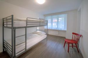 a bedroom with two bunk beds and a red chair at Beausite Apartments in Interlaken