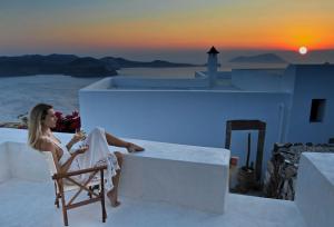 a woman sitting in a chair on a ledge watching the sunset at Plaka Suites in Plaka Milou