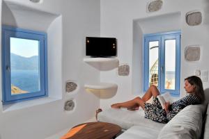 a woman sitting on a couch reading a book at Plaka Suites in Plaka Milou