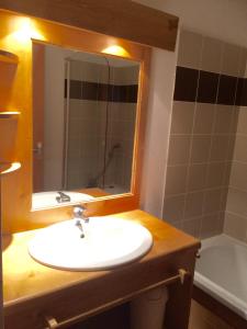 La salle de bains est pourvue d'un lavabo, d'un miroir et d'une baignoire. dans l'établissement Vacancéole - Résidence Central Park, à La Foux