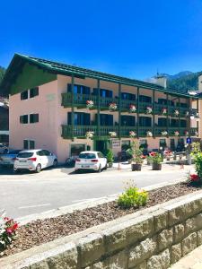 a pink building with cars parked in a parking lot at Hotel Zeni in Madonna di Campiglio