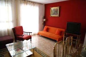sala de estar con sofá naranja y TV en Apartamento San Carlos, en Sant Carles de la Ràpita