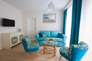 a living room with a blue couch and chairs at Ava Apartamenty in Niechorze