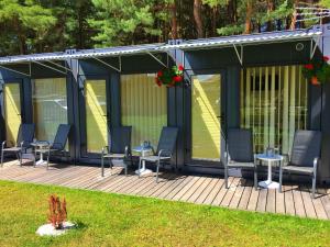 a house with chairs and tables on a deck at Karavanai "Aušroje" in Šventoji