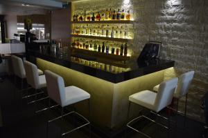 a bar with white chairs and alcohol bottles at Hotel Zefyros in Paralia Katerinis