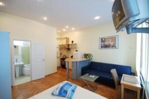 a living room with a blue couch and a kitchen at Kaunas Apartments in Kaunas