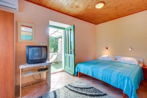 a bedroom with a bed and a tv and a door at Apartments Josip & Maria in Veli Lošinj