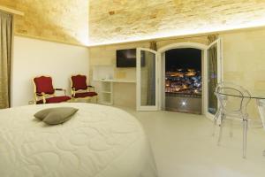 a bedroom with a bed and two chairs and a window at Antica Torre di Iuso in Matera
