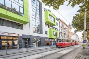 eine rote Straßenbahn auf einer Stadtstraße mit Gebäuden in der Unterkunft Mar Suite Apartments - Simmering in Wien