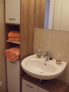 a bathroom with a sink and a mirror and towels at Jázmin Deluxe Apartman in Harkány