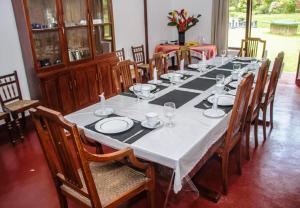 a long table with plates and wine glasses on it at Ancoombra Tea Estate Bungalow in Matale