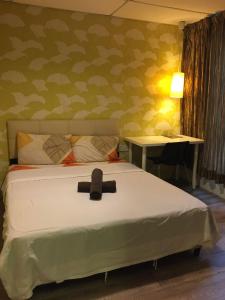 Una cama con una cruz negra en una habitación en 7 Star Hotel, en Kota Damansara