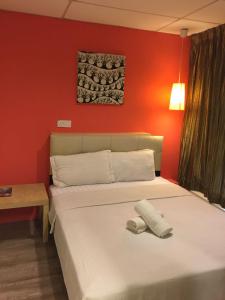 um quarto com uma cama branca e uma parede vermelha em 7 Star Hotel em Kota Damansara