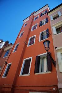 a red building with white windows and a street light at Ca' Zuliani Rooms in Chioggia