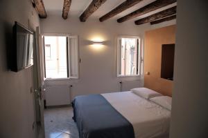 a bedroom with a bed and two windows at Ca' Zuliani Rooms in Chioggia