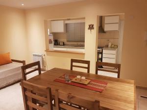 cocina y comedor con mesa de madera y sillas en Departamentos del Valle Tandil en Tandil