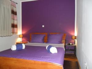 um quarto com paredes roxas e uma cama com almofadas em Apartment Ivan em Trogir