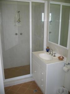 a white bathroom with a shower and a sink at Harriet Place apartment in Darwin