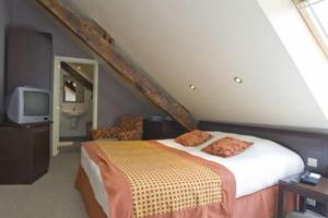 sypialnia na poddaszu z łóżkiem i telewizorem w obiekcie Hotel Les Mignees w mieście Barvaux-sur-Ourthe