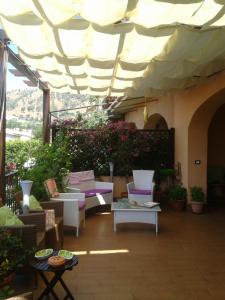 un patio con sillas, mesas y una sombrilla grande en Residence a 150 metri dal mare e dalla scogliera di Pietragrande - Montauro, en Montauro