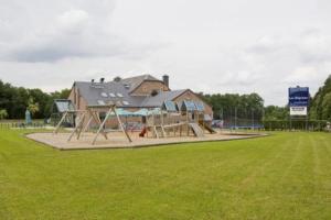 ein Spielplatz auf einem Feld mit einem Haus in der Unterkunft Hotel Les Mignees in Barvaux