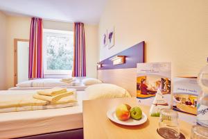 een hotelkamer met 2 bedden en een tafel met een fruitschaal bij DJH Jugendherberge Hagen in Hagen