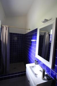 a blue tiled bathroom with a sink and a mirror at La Caprine in Gordes