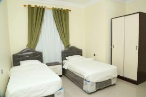a bedroom with two beds and a mirror at Golden Season Furnished Apartments 5 in Salalah