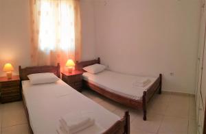 two beds in a room with two lamps and a window at Eirini- Ioanna in Sami