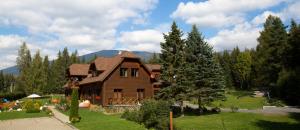 a large wooden house in the middle of a yard at Penzion Sileo in Pribylina