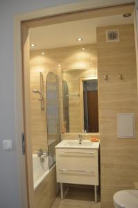 a bathroom with a sink and a tub and a mirror at Apartament Telimena in Olsztyn