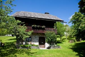 eine alte Scheune mit einem Dach auf einem grünen Feld in der Unterkunft Domačija Koklej - Apartments Vintage Vacation in Luče