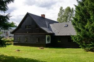 a black barn with a gambrel roof at Chalupa Na Paloučku in Orlické Záhoří 