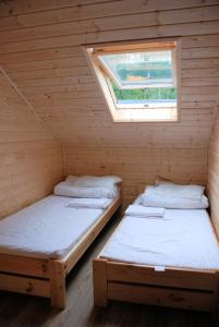 Habitación de madera con 2 camas y ventana en AURUM Domki Letniskowe, en Pogorzelica