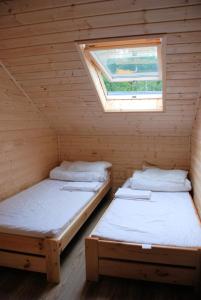 two beds in a wooden room with a window at AURUM Domki Letniskowe in Pogorzelica