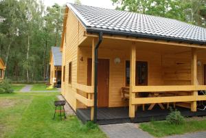 a small wooden cabin with a porch and a stool at AURUM Domki Letniskowe in Pogorzelica