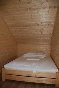 Cama en habitación de madera con techo de madera en AURUM Domki Letniskowe, en Pogorzelica