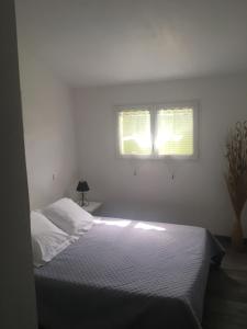 ein weißes Schlafzimmer mit einem Bett und zwei Fenstern in der Unterkunft Villa Mer Et Montagne in Macinaggio