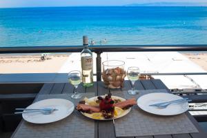 un tavolo con un piatto di cibo e una bottiglia di vino di Thermaikos studios & apartments a Perea