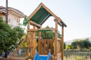 a wooden play house with a slide at Vanessa's Rooms & Apartments in Kanali