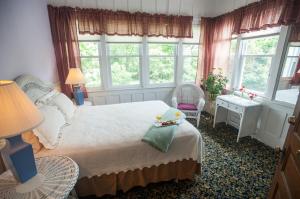 a bedroom with a bed and two chairs and windows at Market Street Inn in Taylorville