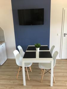 a white dining room table with white chairs and a tv at Apartament Silver in Pogorzelica