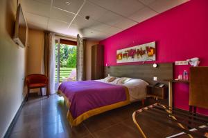 - une chambre avec un mur rose, un lit et une chaise dans l'établissement Logis Hôtel Restaurant Le Chalet du Mont Roland, à Dole
