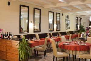 uma sala de jantar com mesas, cadeiras e espelhos em Logis Hôtel Restaurant Les Cèdres em Joyeuse