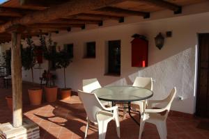 a patio with a glass table and white chairs at El Balcón del Huéznar in Cazalla de la Sierra