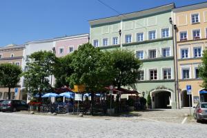 a group of buildings with tables and umbrellas on a street at Bayerischer Hof in Burghausen