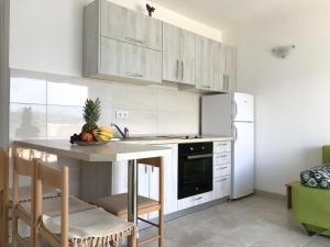 a kitchen with white cabinets and a table with fruit on it at Franovic Apartments in Tivat