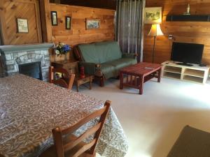 a living room with a bed and a couch and a television at Baywatch Lighthouse Cottages & Motel in Brackley Beach