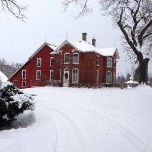 duży dom z czerwonej cegły ze śniegiem w obiekcie Strawberry Farm B and B w mieście Muscatine