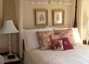 1 cama con almohadas blancas y 2 cuadros en la pared en Strawberry Farm B and B, en Muscatine